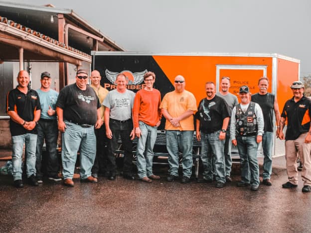 A full ProRider class standing together in front of the training trailer