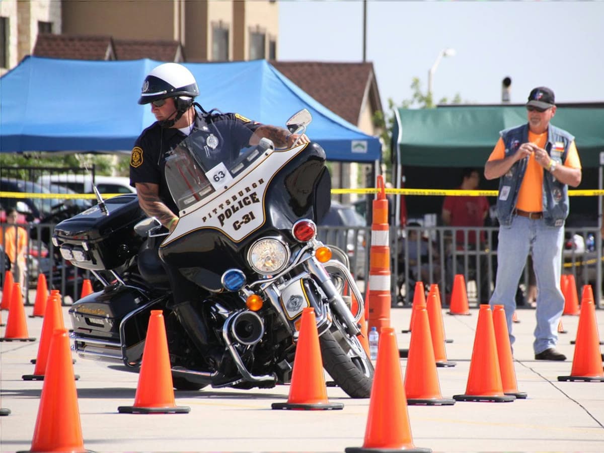 A police motor officer leaned hard through a tight line of cones at low speed